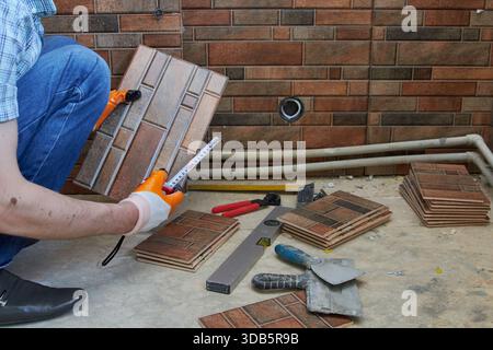 measure the size of the tile, laying tile on the wall in the kitchen Stock Photo
