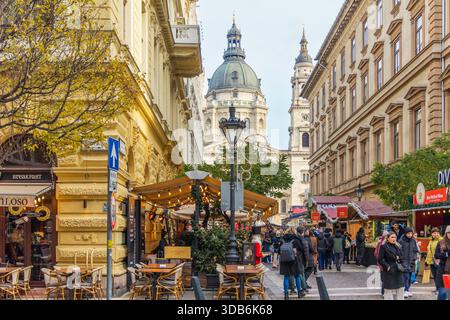 BUDAPEST, HUNGARY - DECEMBER 18, 2025: Horizontal eye level medium shot of people at a Christmas market food stall with festive decorations Stock Photo