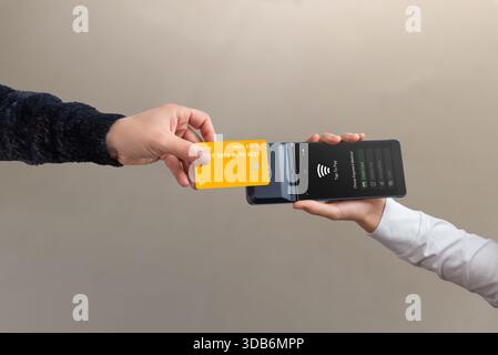 Contactless credit card tap to pay on mobile POS terminal held by cashier, showing modern wireless payment and digital checkout process Stock Photo