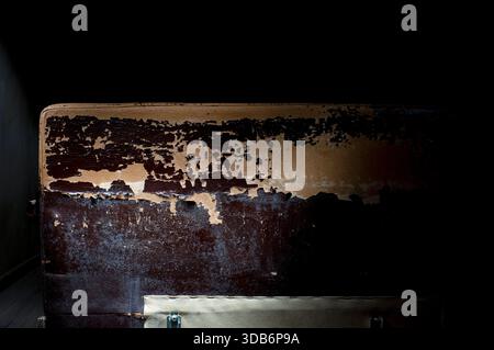 Damaged dark synthetic leather sofa. Old cracked damaged leather on synthetic leather sofa upholstery. Stock Photo