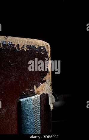 Damaged dark synthetic leather sofa. Old cracked damaged leather on synthetic leather sofa upholstery. Stock Photo