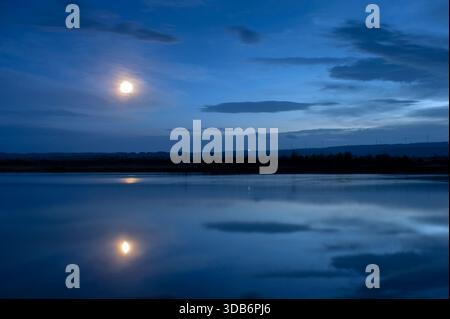 Night fishing with fishing rods on the lake shore.Fishing rods on a holder near the lake. Stock Photo