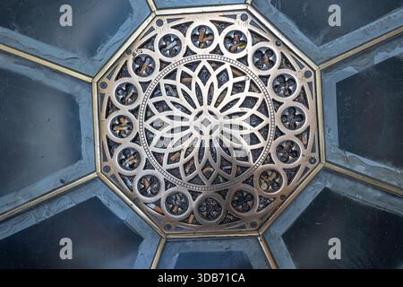 An ornate metal grate forms a circular floral mandala at the center of an octagonal ceiling panel, blending architectural detail with geometric symmet Stock Photo