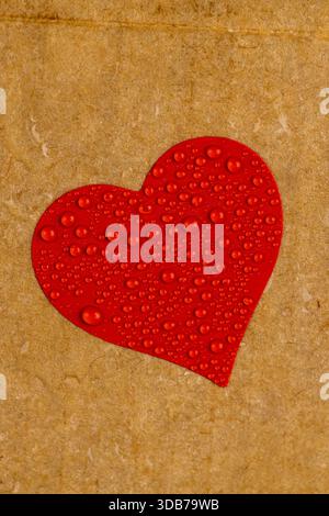 wet hard yellow cardboard for packaging goods and products with red plastic hearts glued on , a piece of corrugated cardboard with heart covered with Stock Photo