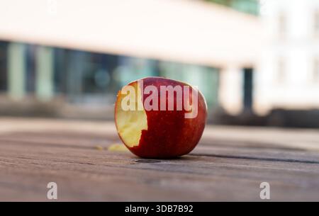 One red ripe bitten apple on a wooden table. Farm products. Dietary and vegan products Stock Photo