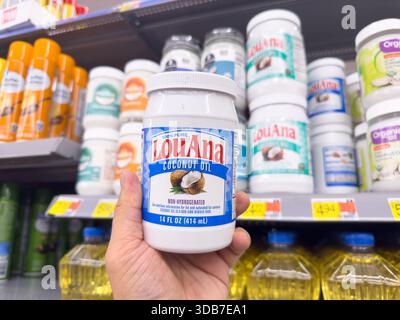 Los Angeles, California, United States - 09-30-2023: A view of a hand holding a container of LouAna coconut oil, on display at a local grocery store. Stock Photo