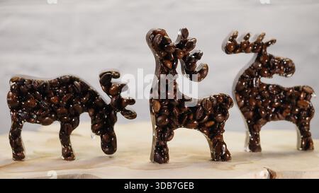 Three handmade elk figurines crafted from real coffee beans, arranged as a decorative winter and Christmas set. This creative coffee art concept combi Stock Photo