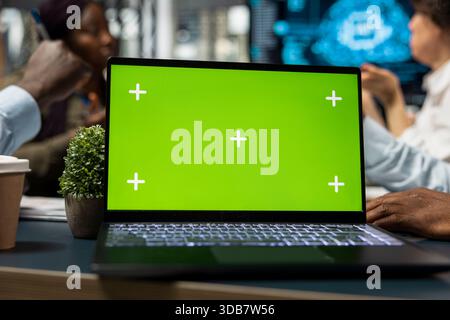 Green screen laptop used by AI company programmers doing brainstorming to create deep learning models. IT employees cooperating on artificial intelligence project using chroma key notebook Stock Photo