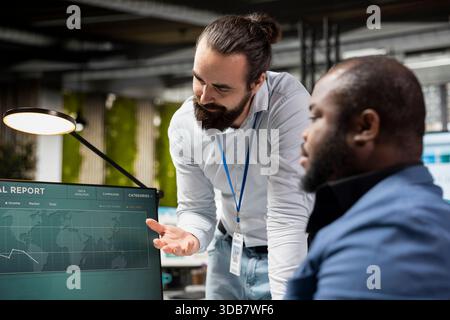 Diverse associates team in a modern office collaborates on project planning, using charts and analytics to drive performance and success while fostering work alliance and synergy. Stock Photo