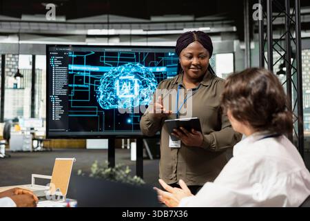 IT professionals doing meeting in company conference room, implementing AI solutions to increase productivity. Multiethnic technicians discussing machine learning models roadmap in startup office Stock Photo