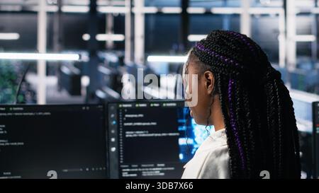 Technicians in data center review AI diagnostics, analyzing neural network performance to maintain operational reliability. IT workers optimize artificial intelligence systems configuration, camera A Stock Photo