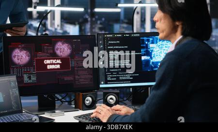 System administrators in data center struggle with computer bugs while using AI. Frustrated server farm coworkers doing brainstorming to fix system errors while using artificial intelligence, camera A Stock Photo