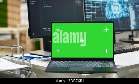 Chroma key notebook in AI industry startup workspace leveraging machine learning technology. Empty startup office with isolated screen laptop and artificial intelligence program running on monitors Stock Photo