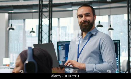 System administrator in office developing software applications, integrating AI driven automation in operations. IT expert using laptop, debugging applications to resolve issues, camera A Stock Photo