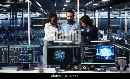 Portrait of smiling engineers in server room using AI to review infrastructure diagnostics. Cheerful IT coworkers in data center analyzing performance data using artificial intelligence, camera A Stock Photo