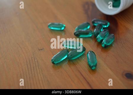Green Ibuprofen Liquid Gel Capsules Spilled on a Wooden Table Stock Photo