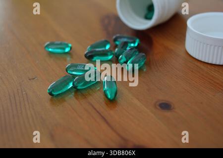 Green Ibuprofen Liquid Gel Capsules Spilled on a Wooden Table 2 Stock Photo