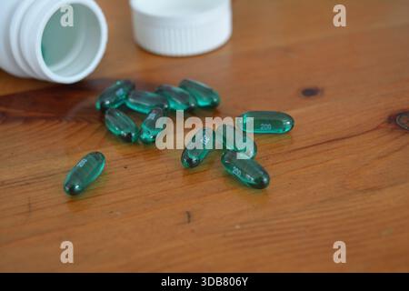 Green Ibuprofen Liquid Gel Capsules Spilled on a Wooden Table 3 Stock Photo