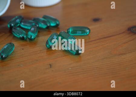 Green Ibuprofen Liquid Gel Capsules Spilled on a Wooden Table 4 Stock Photo