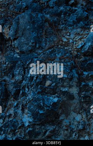 Rugged stone and rock surface with deep blue and gray tones, showcasing natural geological texture suitable for abstract backgrounds, earth materials, Stock Photo