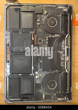 Laptop interior showing motherboard, fans, and battery cells covered in dust, needing maintenance Stock Photo