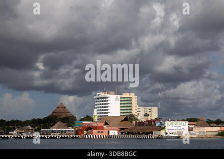 Storm clouds gather over the waterfront in Cozumel, Mexico, with Margaritaville Cozumel and nearby hotels lining the shore across the harbor. Stock Photo