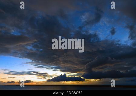 Dramatic tropical sunset with towering storm clouds and golden light over the Caribbean Sea off the coast of Belize. Stock Photo