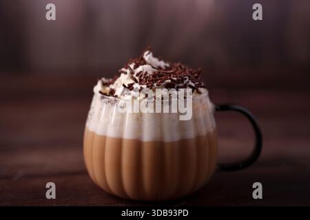 warm coffee beverage topped with whipped cream and chocolate sprinkles in a glass cup with a dark background, creating a cozy and inviting atmosphere, Stock Photo