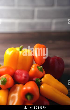 vibrant array of colorful bell peppers on wooden surface with blurred brick wall background in warm, inviting lighting showcasing freshness and variet Stock Photo