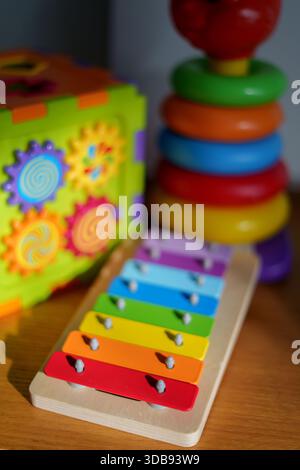 vibrant childrens play scene featuring colorful xylophone, stacking rings, and gear puzzle on wooden surface in sunlit room creating a fun and educati Stock Photo