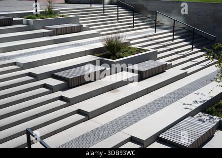 modern urban staircase featuring concrete steps, wooden benches, and integrated planters in a geometric and symmetrical outdoor design with natural li Stock Photo