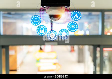 Security camera with digital interface icons showing surveillance, monitoring, alerts, and protection inside a modern building, representing smart tec Stock Photo