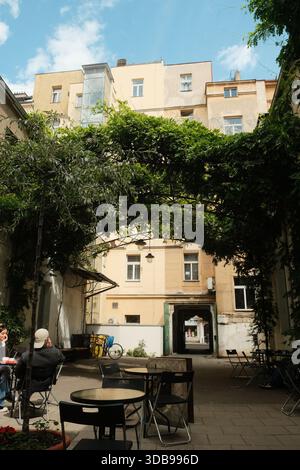 Charming courtyard scene, featuring lush greenery and a vintage building, offering peaceful outdoor living. Stock Photo