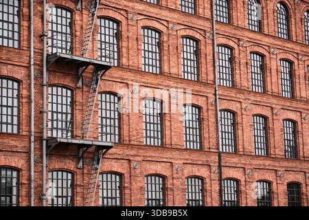 Panoramic red brick industrial facade with repeating windows, suitable as urban architectural background for design or real estate. Stock Photo
