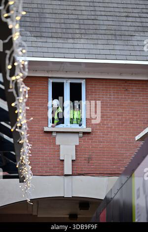 Two Construction Workers Installing a Window on Brick Building Stock Photo