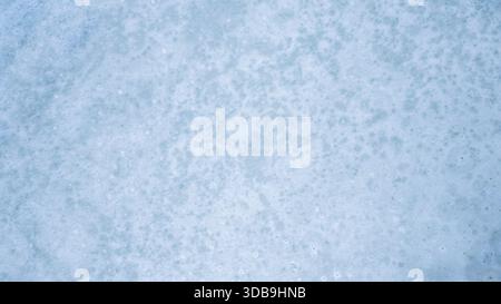 Aerial view of a vast, frozen expanse under the pale sky, the icy surface textured with subtle patterns, creating a tranquil scene, Hofn, Sveitarfelag Stock Photo