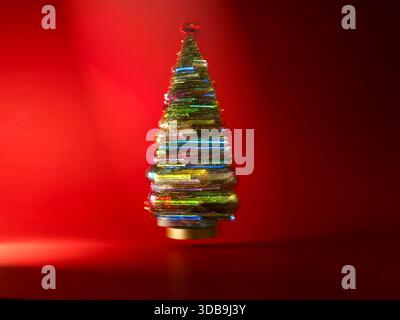 Close-up of a colourful glass Christmas tree ornament in front of a red background Stock Photo