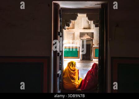 Quiet moments in color: two women in saris resting on the steps of an Indian doorway. Stock Photo