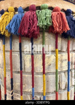 Colorful wool tassels on a traditional textile against a brick wall Stock Photo