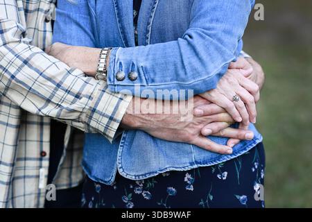 Close-up of couple's hands embracing gently outdoors. Stock Photo