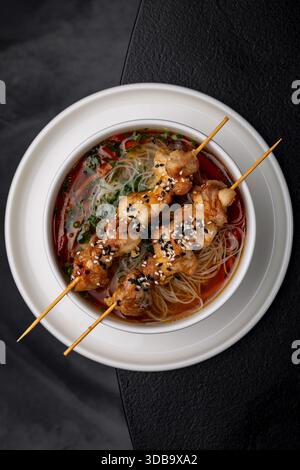 Asian soup with fish and meat skewers on top isolated Stock Photo