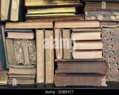 A dense collection of antique and vintage books packed on a shelf Stock Photo