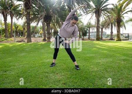 Woman doing side stretch exercise outdoors in a park Stock Photo