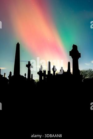 Aurora borealis over silhouetted monuments in Glasgow Necropolis at night, Scotland, UK Stock Photo