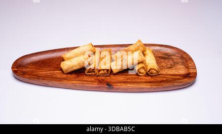 Crispy fried spring rolls served on wooden board isolated on white background. Stock Photo