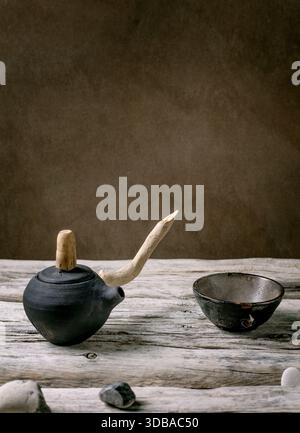 Original handmade ceramic teapot with wooden handle and cups for traditional Chinese tea drinking on an old wooden table. Decorative sea pebbles all a Stock Photo