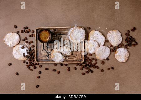 Homemade shortbread cookies dusted with powdered sugar. Rustic dessert, homemade pastry. Cup of espresso with coffee beans on ceramic tray. Background Stock Photo