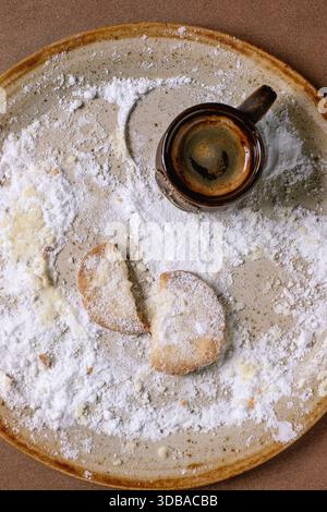 Last broken cookie. Homemade shortbread cookie dusted with powdered sugar with cup of freshly brewed espresso. Background in the 2025 Color of the Yea Stock Photo
