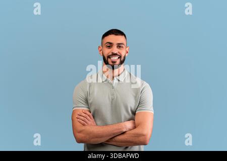 Smiling Man With Beard Poses Confidently Against a Blue Background in a Casual Setting Stock Photo