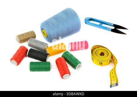 A collection of sewing supplies, including spools of colorful thread, a bright yellow tape measure, and blue thread snips, Stock Photo